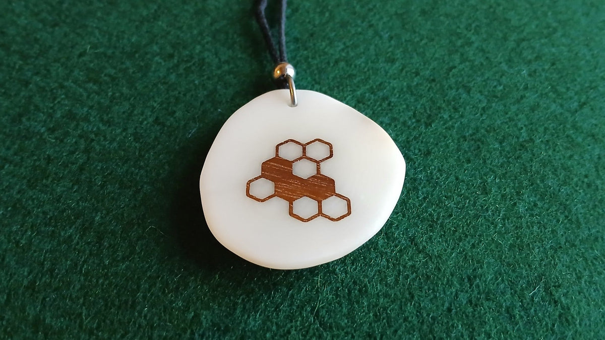 Bijou en tagua : pendentif au motif nid d'abeille incrusté de bois, finition lustrée, sur feutrine verte